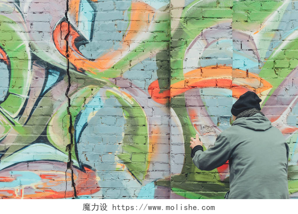一个在墙壁上涂鸦的男人人的背观画墙上五颜六色的涂鸦